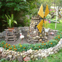 Moulin en pierre fait maison dans un lit de fleurs de jardin