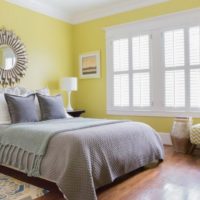 Yellow walls and gray bedspread in the bedroom 12 sq m