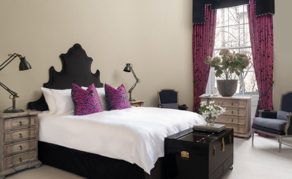 Fehér ágytakaró fekete ágyon és párnák lila takarókban