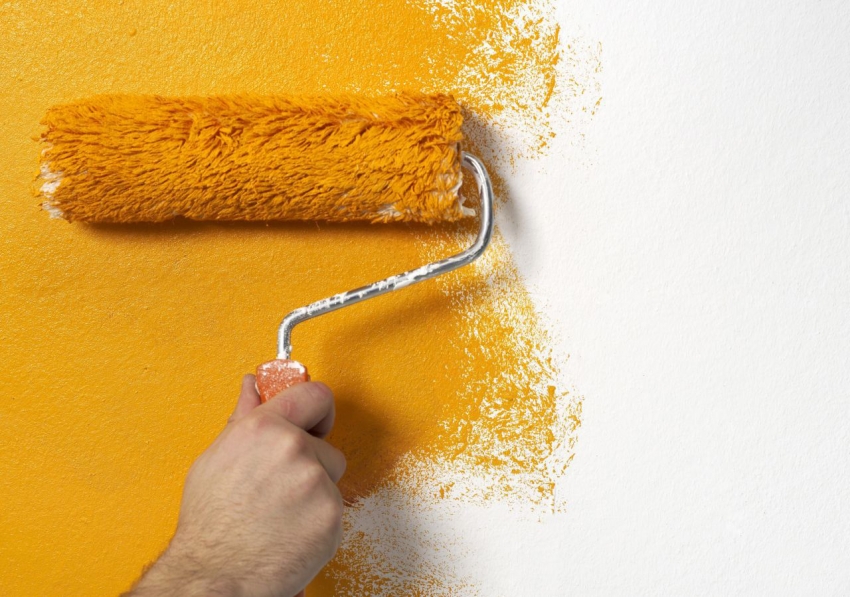 Peinture papier peint sur le mur avec un rouleau en orange