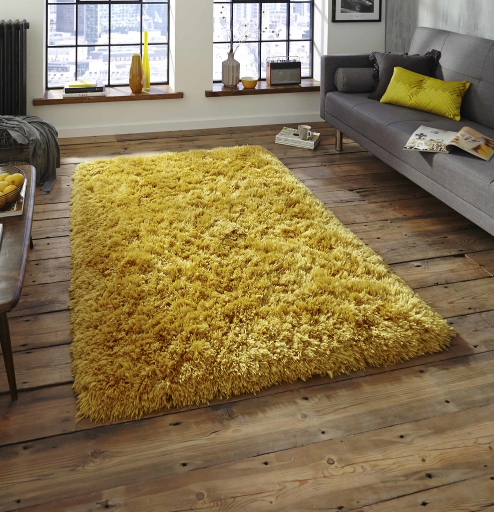 Dzeltens paklājs uz koka grīdas tumšā guļamistabā