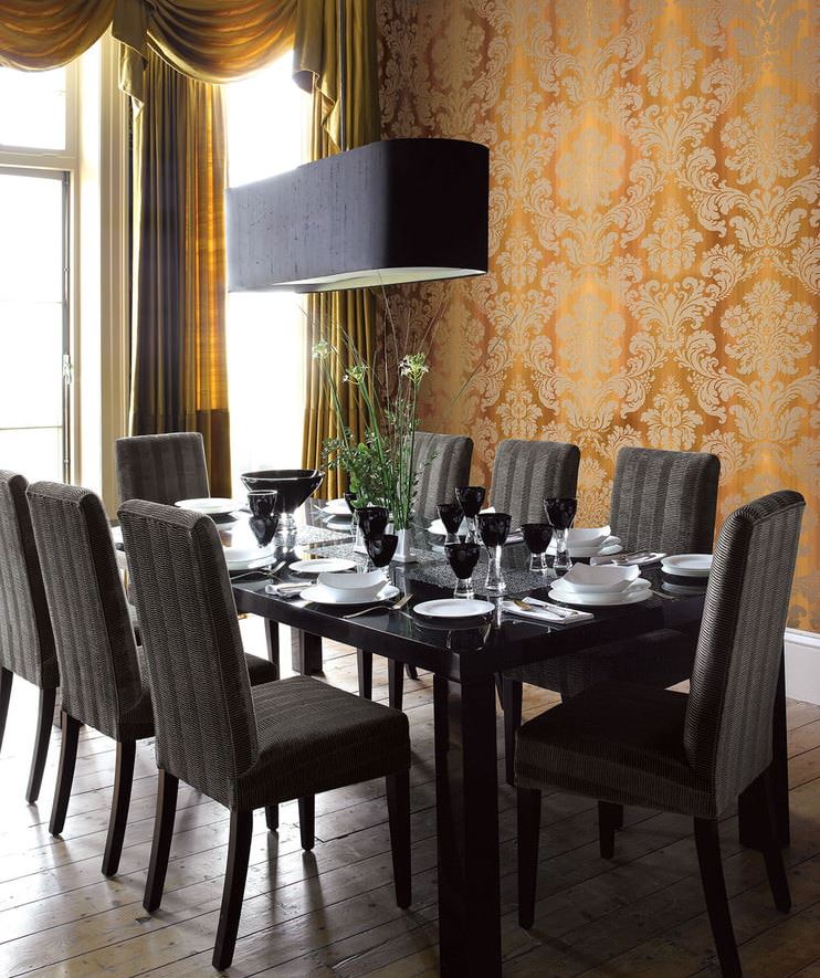 Chaises noires à la table à manger dans une pièce avec papier peint en or foncé