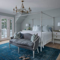 Интериор на спалня в пастелен цвят с полилей на тавана