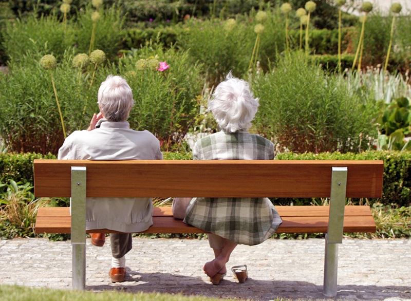 Elderly people relax on a wooden bench in a leisure park