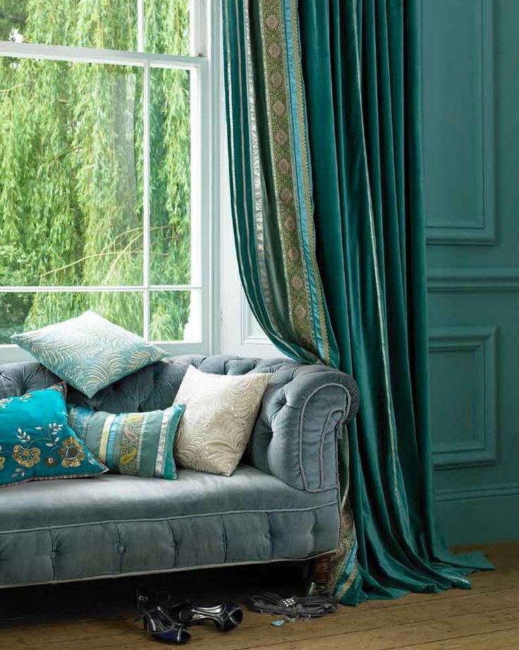 Sofa in front of living room window with emerald curtains