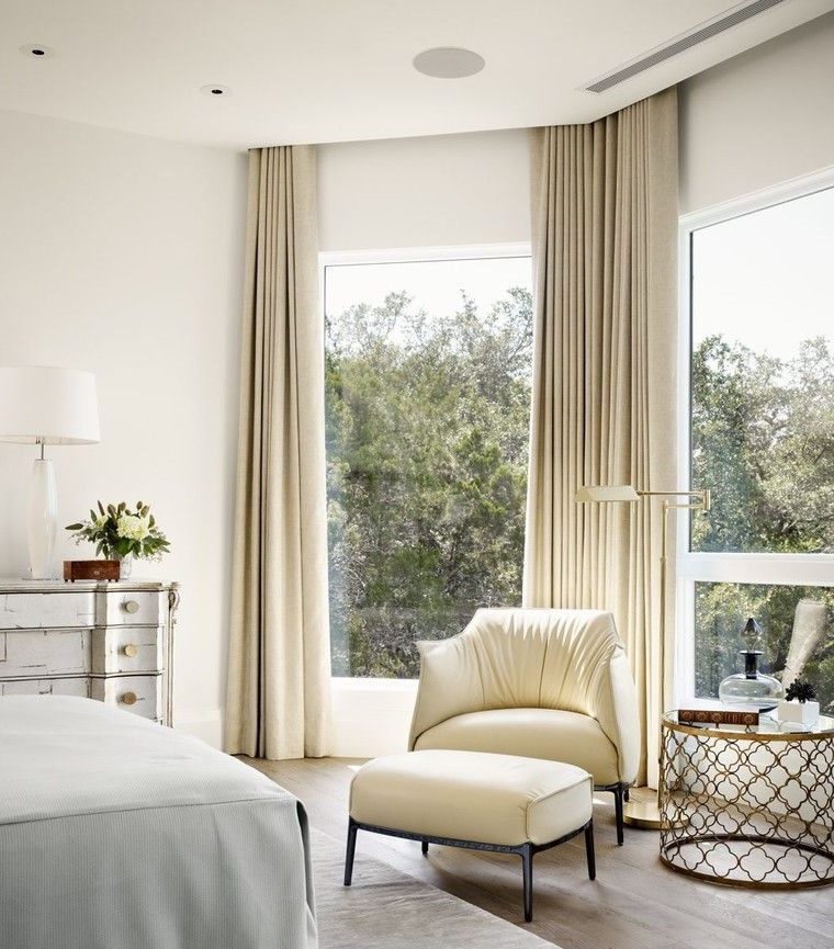 Alte finestre della camera da letto con tende beige