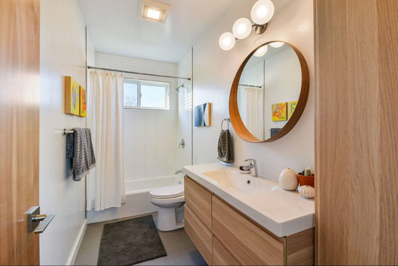 Apaļais spogulis uz apvienotās vannas istabas sienas