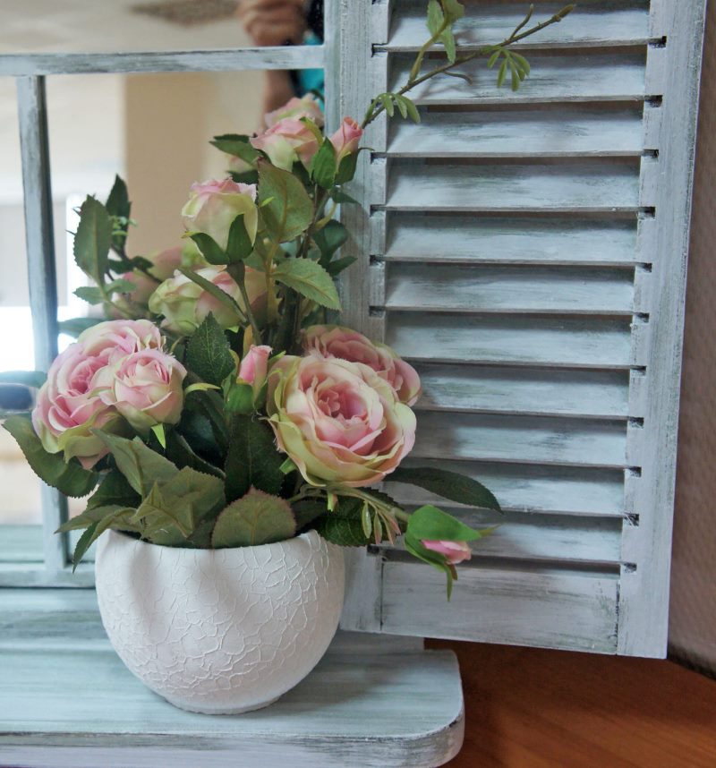 Vaso delle rose di fioritura su un davanzale di legno