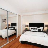 Mirror wall in bedroom with white bed