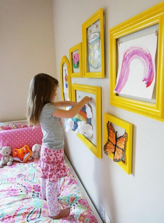 La fille décore la pièce avec ses propres dessins.