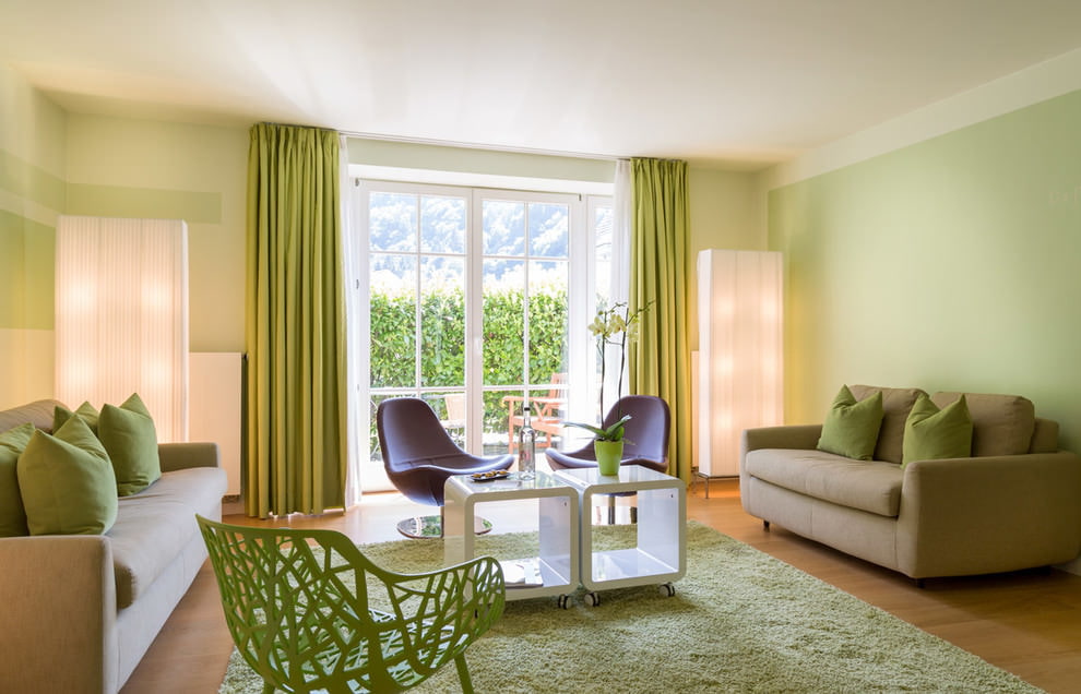 Bāli zaļas sienas viesistabā ar diviem dīvāniem