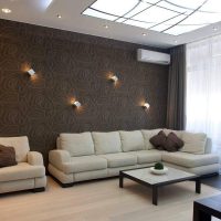 Smėlio spalvos sofa kambaryje su rudais tapetais