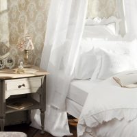 Antiek nachtkastje dichtbij een wit bed