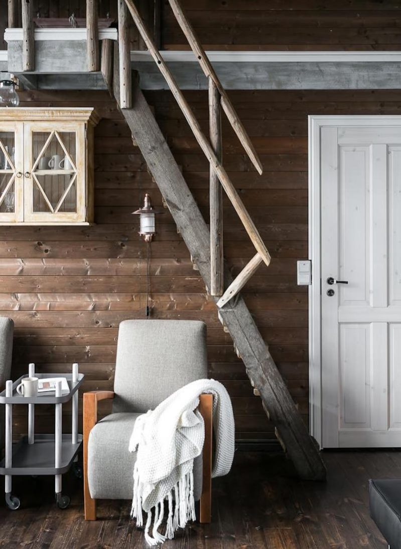 Fauteuil gris sous un escalier raide jusqu'au deuxième étage d'une maison en bois