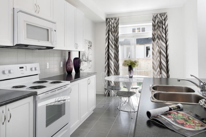 Modernaus stiliaus virtuvės interjeras su pilkomis užuolaidomis.